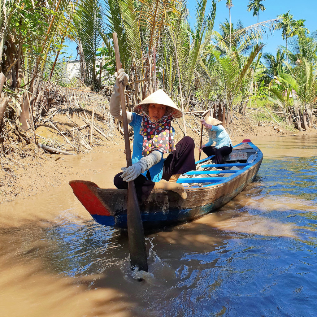 Sailing on a sampan on a narrow canal in the Mekong Delta