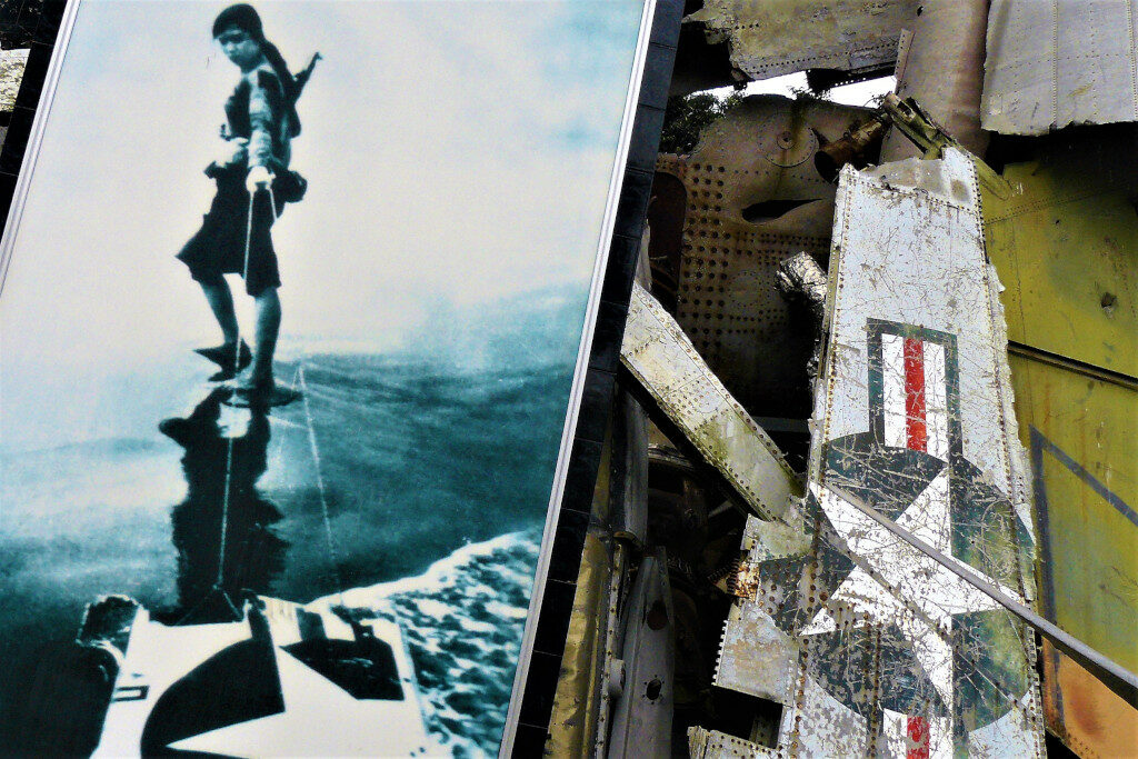 Close up of the downed B-52 bomber with a black and white photograph of a Vietnamese soldier dragging a piece