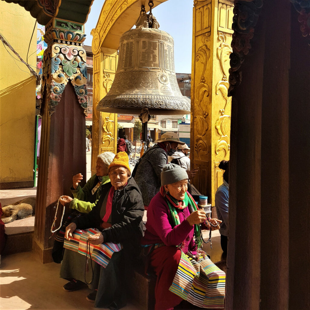An old Tibetan looks on as she takes a break under the big bell at Boudhanath