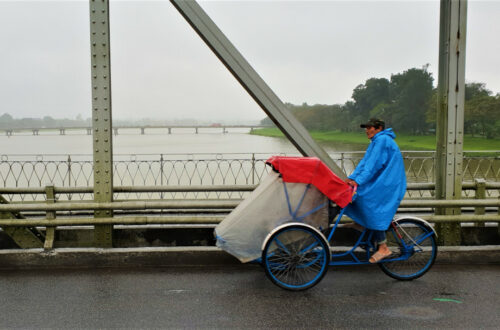 A rikshaw driver cycles his bike on the Truong Tien Bridge