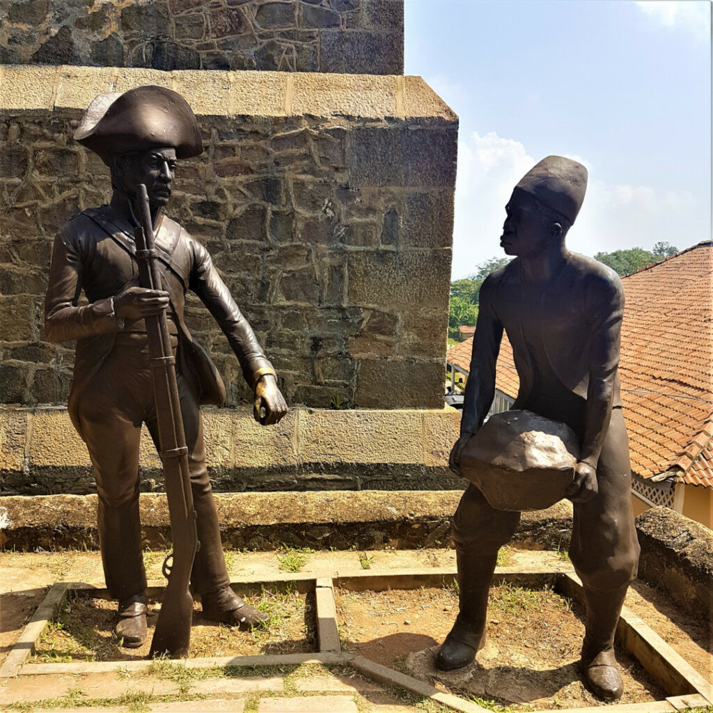 A statue of a Dutch soldier ordering a labourer