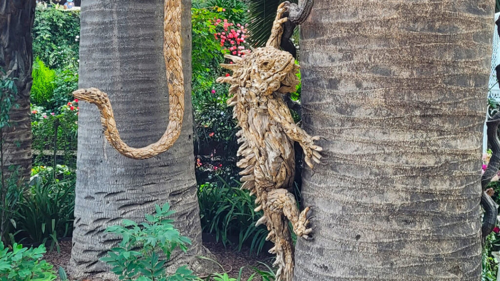 Intricately designed animal sculptures peer behind tree trunks and branches.
