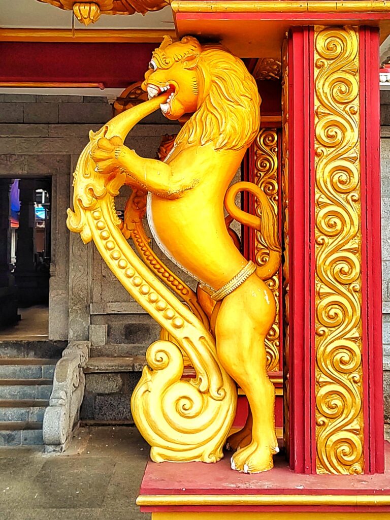 A statue of a lion on one side of the entrance to the temple.